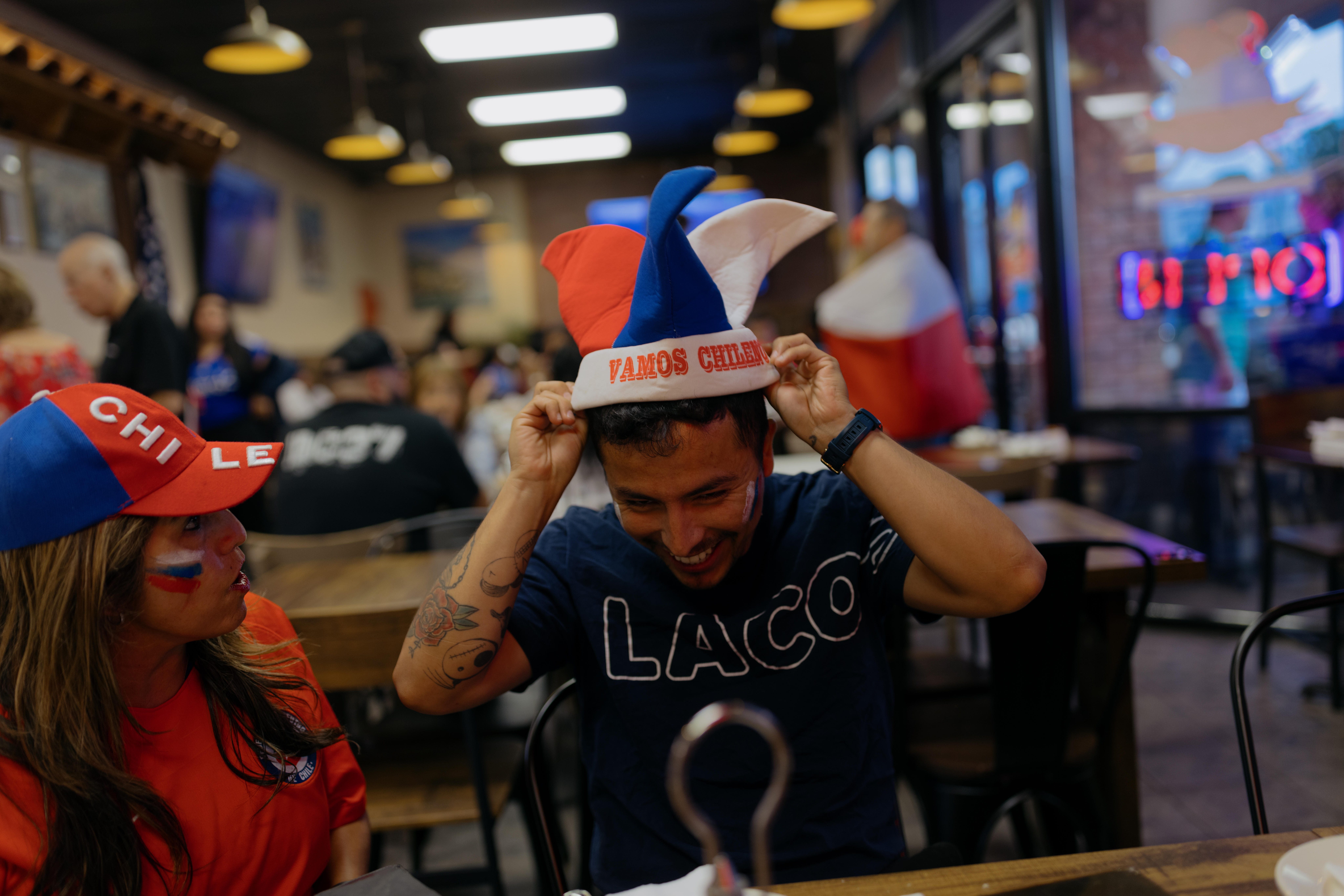 Two people sitting in a food business wearing gear that supports a soccer team